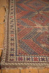 Antique Caucasian rug showing geometric madder red and navy border with visible tatter.