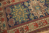 Oversized red floral main border and geometric indigo field on this antique Caucasian rug.