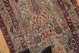Antique Kerman rug's unidirectional design with blossomed foliage, cochineal red, and visible wear.