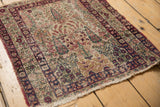 Antique Kerman rug detail: faded foliage, Cyprus tree motifs, and worn secured edge.