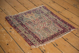 Antique Kerman rug corner, cochineal red and navy border patterns, secured side, and frayed fringe.