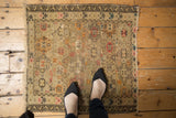 Geometric floral motif in blush, tangerine, charcoal on antique Caucasian rug with even wear.