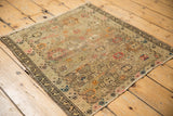Muted beige, blush, and tangerine geometric motifs on the antique Caucasian square mat.