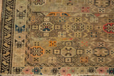 Antique Caucasian rug corner close-up: geometric patterns, fringe, worn pile, and visible foundation.