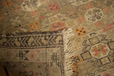 Detail of antique Caucasian hand-knotted rug showing worn beige pile, geometric motifs, and secure overcast edge.