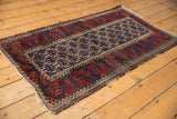 Geometric gul, wave motifs, and meandering vines in cherry red and navy on this Belouch rug.