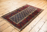 Vintage Belouch rug's tattered side and low pile, featuring cherry red and navy geometric borders.