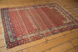 Antique Hamadan rug corner with ruby red field, navy blue, ivory geometric border, worn fringe.