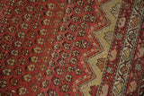 Repeating ruby red boteh motifs and geometric border in saffron, ivory, and brown.