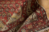 Patina on ruby red, ivory Hamadan rug pile at folded edge with fringe.