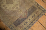 Distressed Oushak rug corner, showing low pile, stepped border with pale mauve and ivory abrash.