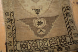 Geometric motif and abrashes within the stepped border of a vintage distressed Oushak rug.