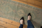 Faded seafoam green and ivory tones on distressed vintage Oushak runner with even wear.