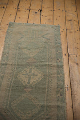 Distressed Oushak runner showcasing worn seafoam green-blue pile and hooked medallion design.