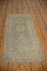 Distressed vintage Oushak runner end, showing worn seafoam green-blue and ivory geometric patterns.