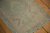 Distressed pile of a vintage Oushak rug runner, showcasing seafoam green and ivory tones with even wear.