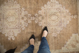 Distressed Oushak carpet with abrashed coffee brown low pile, featuring ivory and mauve medallion.