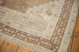 Distressed vintage Oushak rug border with soft pale coffee, ivory, and mauve geometric motifs.