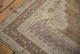 Distressed low pile texture and geometric border details in beige, mauve, and coffee brown.