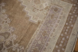 Distressed Oushak rug, low pile with geometric border in mauve and soft brown.