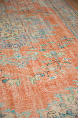 Distressed vintage Oushak rug showing tangerine orange texture, blue details, and visible foundation.