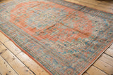 Textural distressed Oushak rug corner, with tangerine, pale blue, and mint vinery motifs.