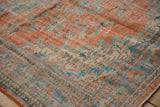 Textured, distressed Oushak carpet showing tangerine, blue, and ivory floral vinery.