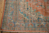 Distressed lower corner of the vintage Oushak rug, showing wear, fringe, and blue and orange borders.