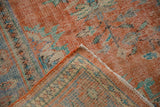 Distressed vintage Oushak corner revealing worn tangerine pile and visible foundation.