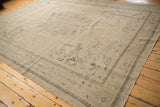 Distressed vintage Oushak rug corner showing geometric border and faded motifs.