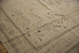 Distressed Oushak carpet with sand tones, low pile texture, and faint brown motifs.