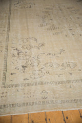 Faded sand and beige Oushak rug texture, showing dark brown patterns and geometric border.