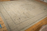 Distressed vintage Oushak carpet with faded sand tones, worn pile, and ghosted grape-leaf motifs.