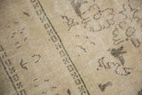 Distressed vintage Oushak pile in sand, beige, and dark brown with expressive linear motifs and even wear.