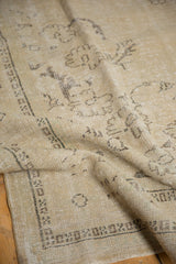 Distressed Oushak rug detail: sand, beige, and faded brown patterns with even wear.