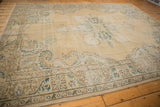 Distressed Oushak carpet border detail showing European scrolling vines and muted hues.