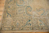 Distressed vintage Oushak rug corner, worn ivory pile with European mallard green vines.