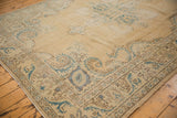 Corner detail of distressed Oushak rug, showing ivory, mallard green scrolling vine border.
