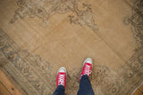 Decorative distressed Oushak rug with sand field, silver motifs, and aged texture.