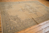 Corner of distressed vintage Oushak rug showcasing wear to knot heads and a faded gray-blue border.