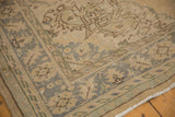 Close-up of vintage distressed Oushak rug corner with muted border pattern and secured fringe.