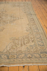 Distressed Oushak corner showing worn sand field, faded silver-beige border, and light fringe.