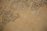 Distressed sand and beige Oushak rug, showing worn curvilinear motifs and exposed knot heads.