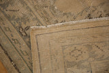 Flipped corner of vintage Oushak carpet revealing hand-knotted foundation and distressed beige pile.