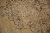 Distressed vintage Oushak rug detail, featuring a subtle pattern in sand, beige, and brown.