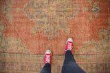 Distressed vintage Turkish Oushak carpet showcasing worn texture in pale brick red, blue, and ivory tones.