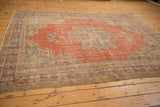 Distressed vintage Oushak carpet detail with worn brick red field and pale green border.