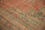 Distressed Oushak rug pile, showing worn knot heads, pale brick red field, geometric border.