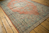 Distressed Oushak rug showing faded cherry red and sky blue floral motifs with visible foundation wear.