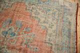 Distressed vintage Oushak carpet texture with faded cherry red, ivory, and sky blue patterns.